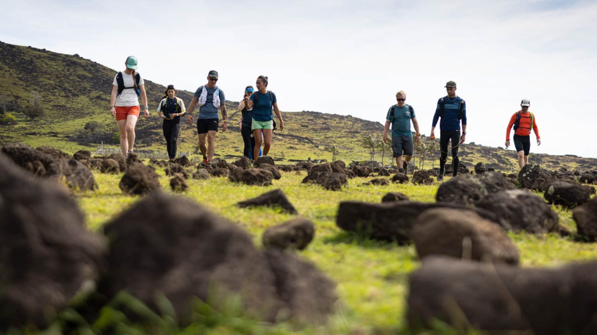 A group of people hiking over rocks and grass.