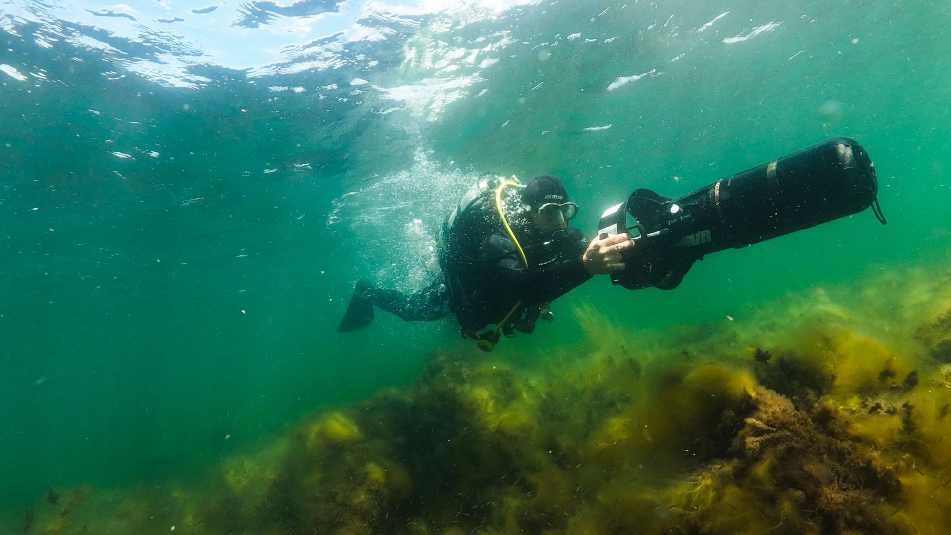 A diver underwater with a camera taking photos of a reef.