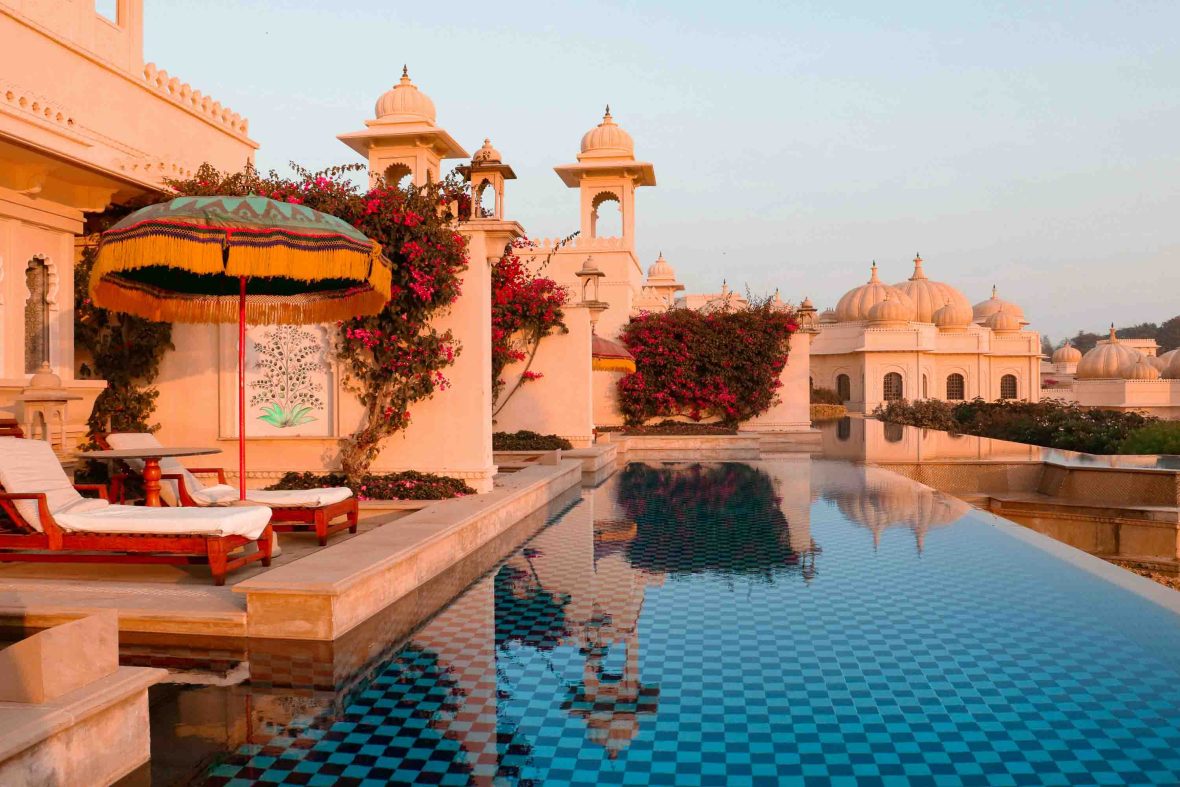 A hotel in India with a pool and deck chairs.