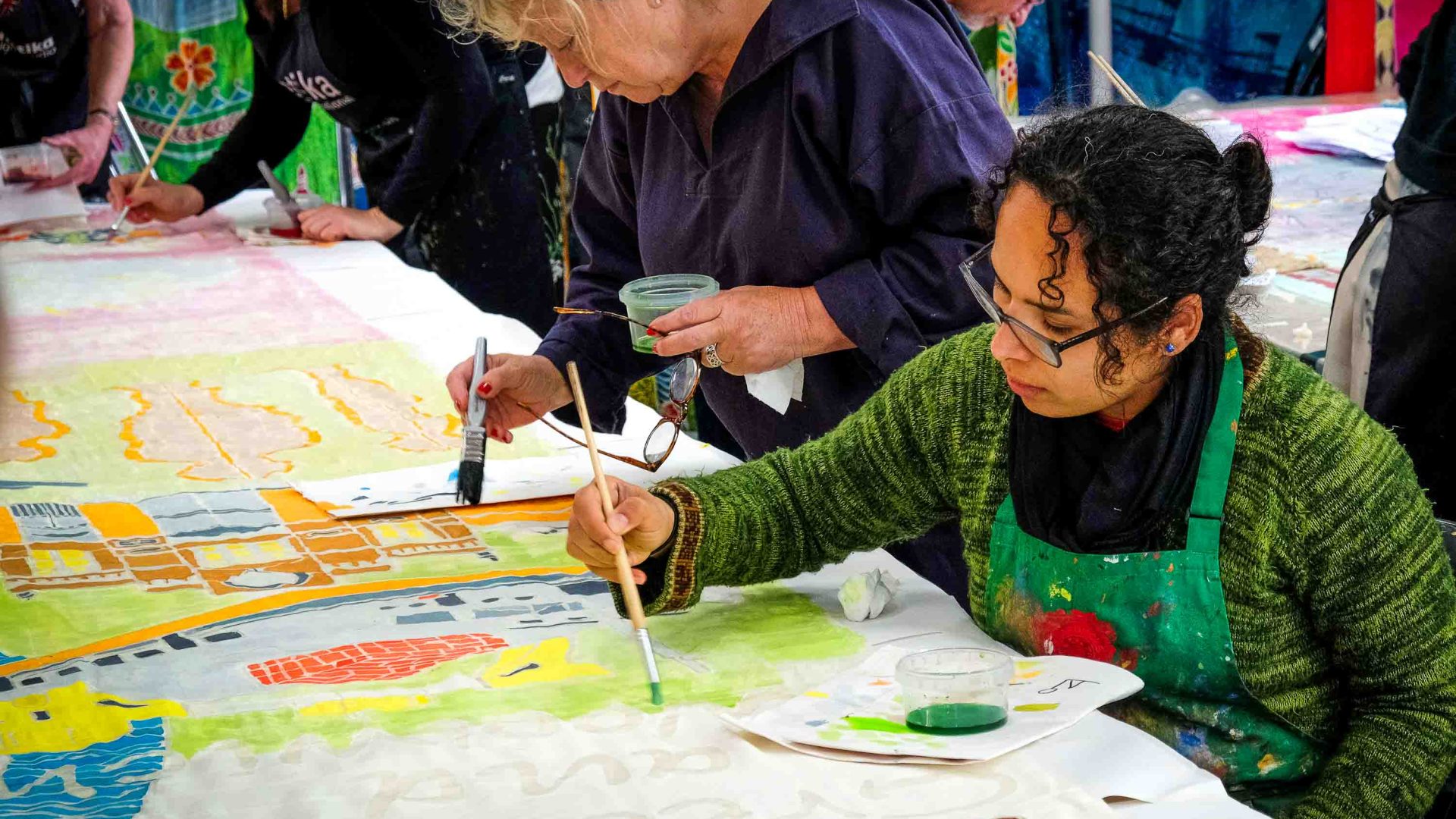 People sat at tables painting silk flags together.