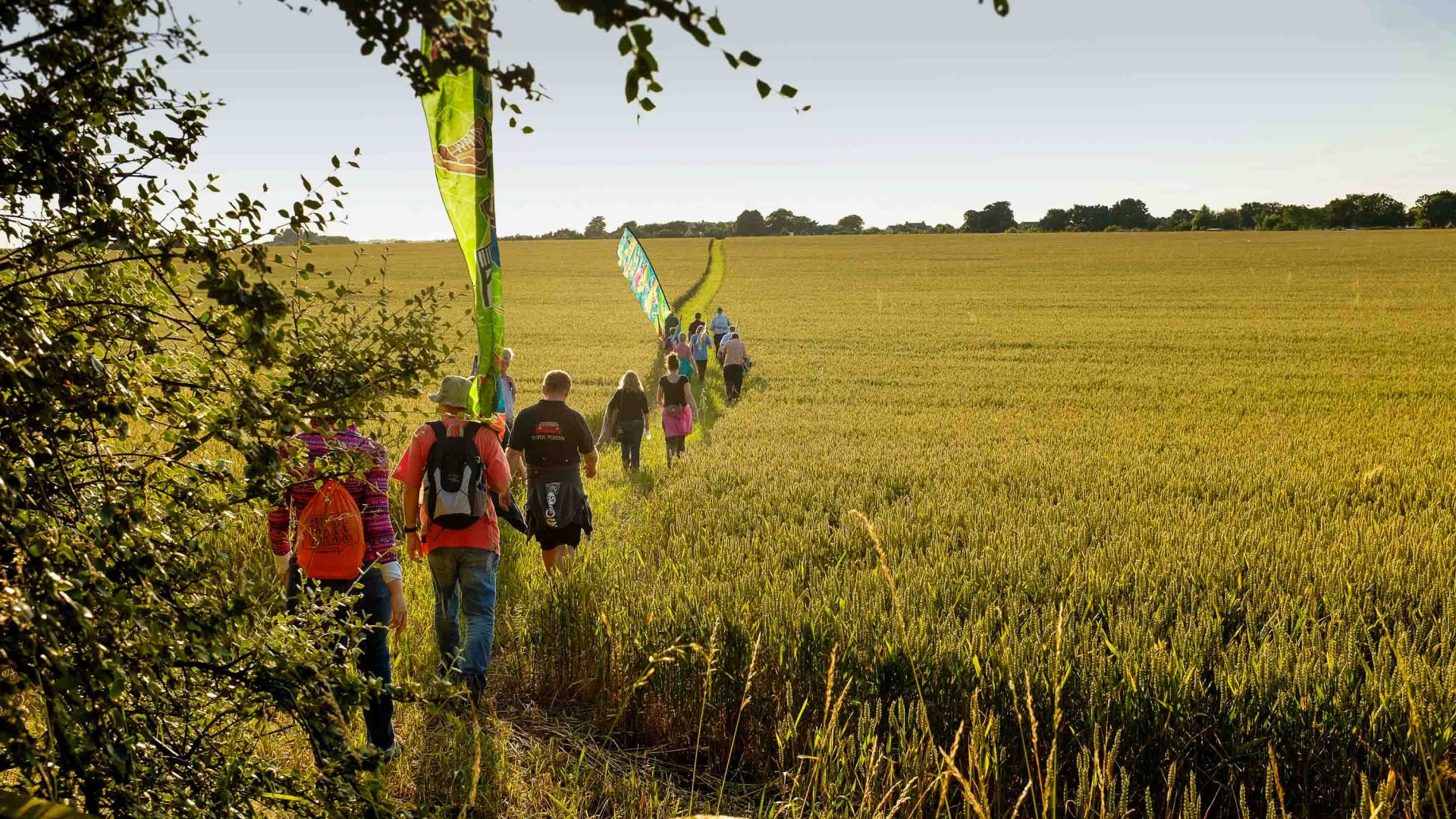Hikers carry silk flags through long grasses.