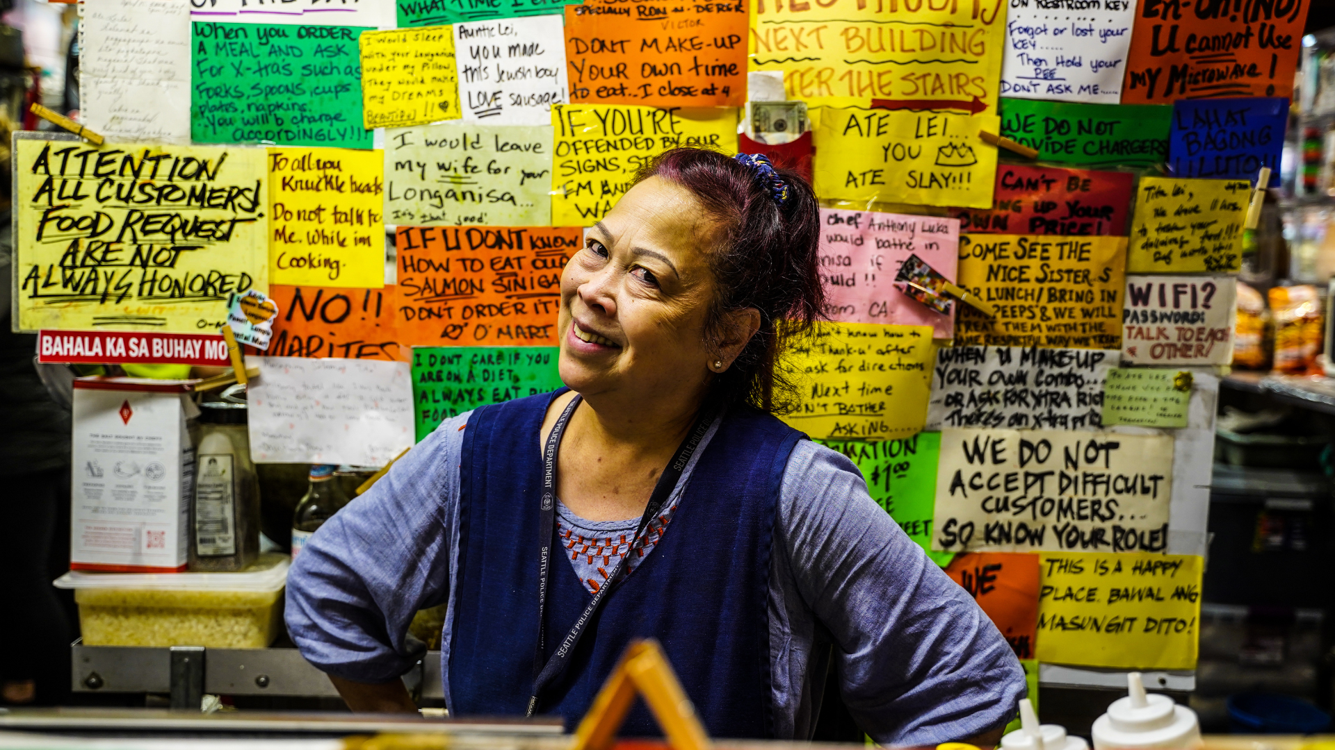 Woman smiles in front of colorful market menus