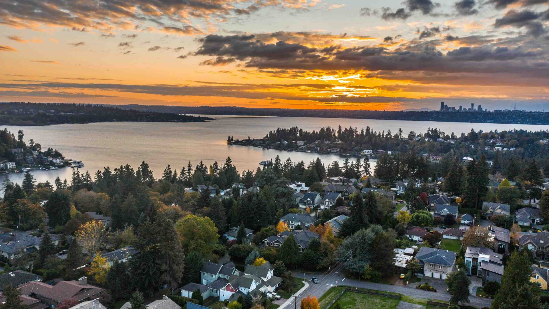 Sunset over a lake, with the skyline of Seattle in the distance.