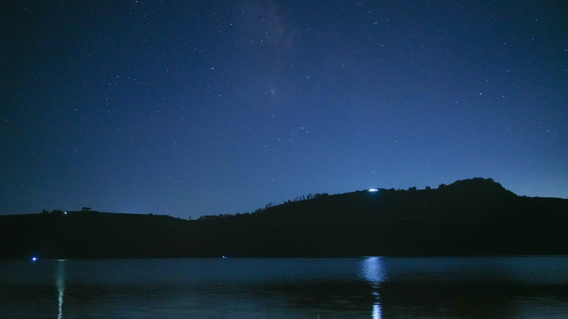 A night sky above a silhouetted island with trees.