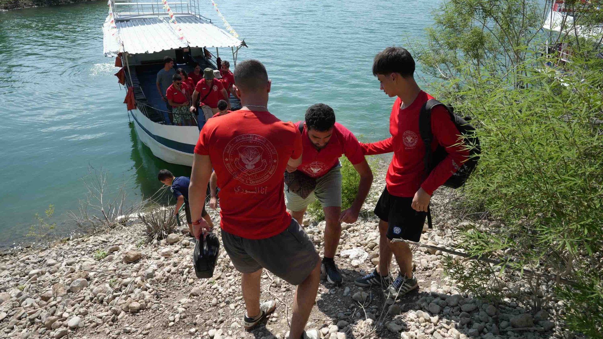 Three men walk up a hill away from a boat.