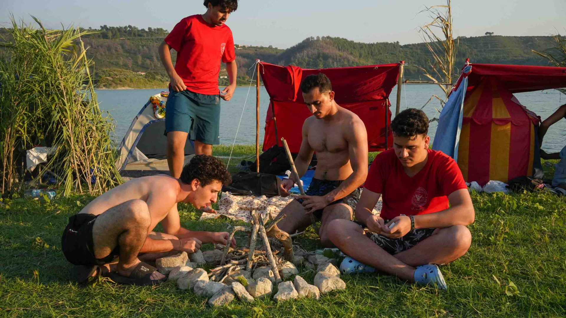 A group of young men prepare a campfire.