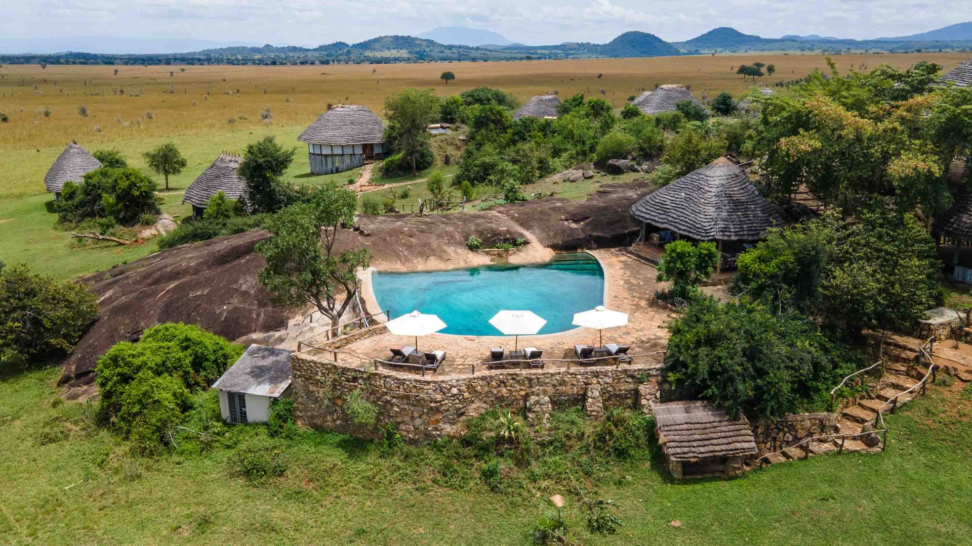 A drone shot of a hotel with a pool in a national park setting.