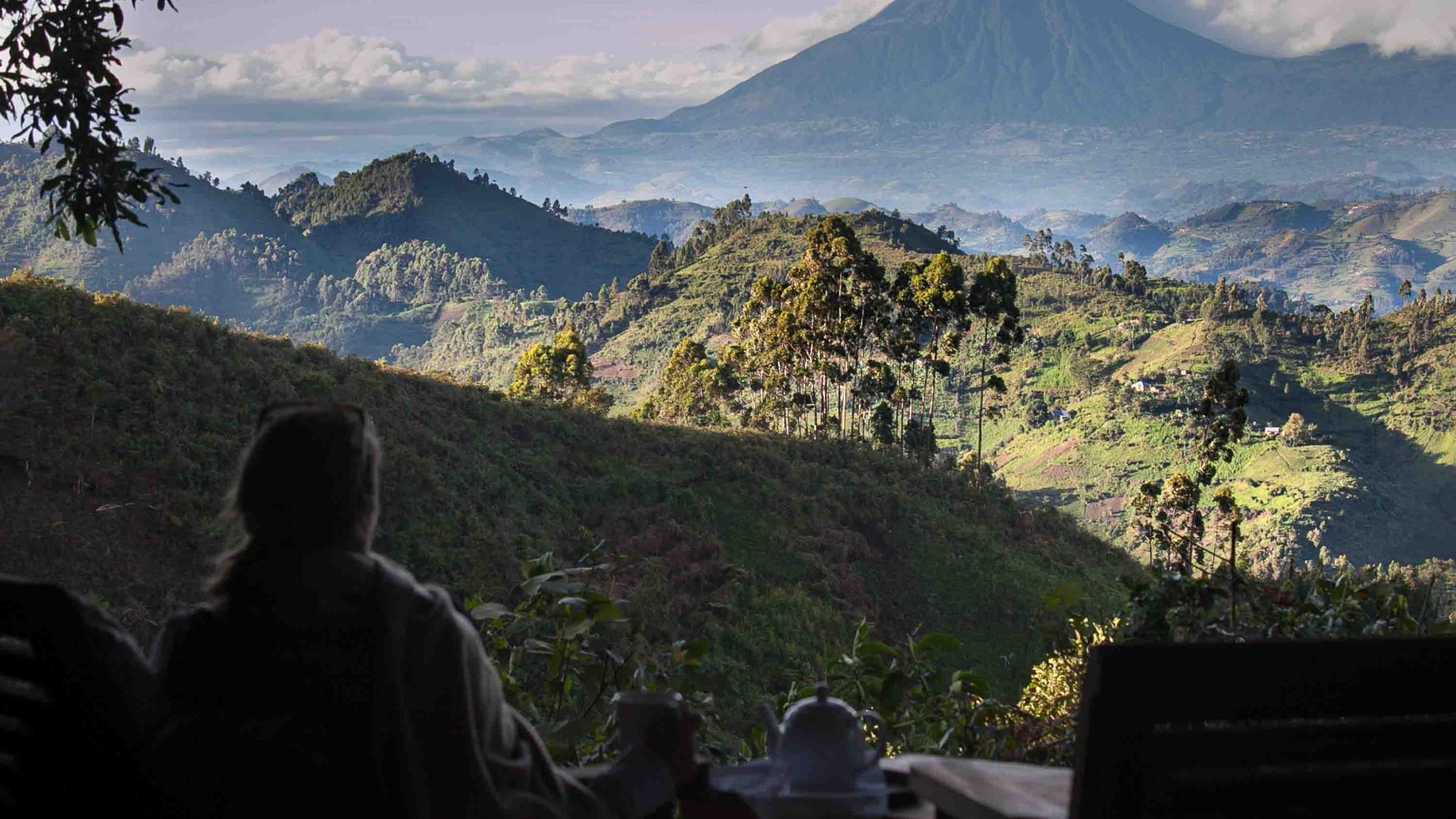 A woman looks out at views of green hills and mountains.