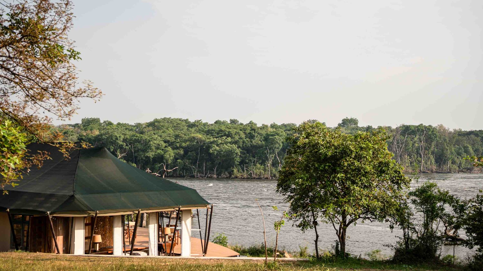 A tented hut looks out over a river.